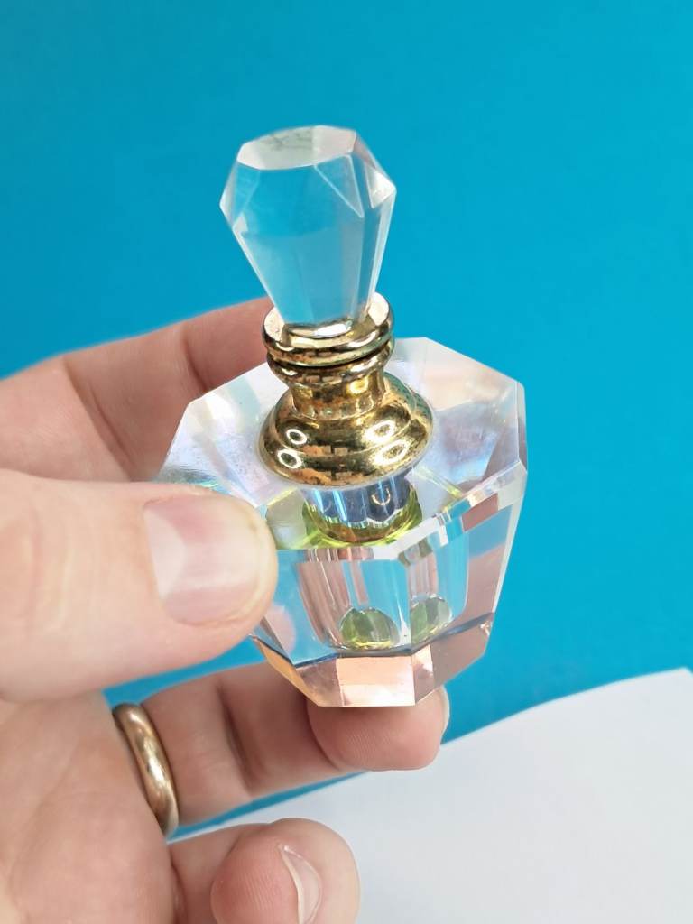 Vintage-style crystal perfume bottle  faceted glass and a gold-tone lid with an applicator.