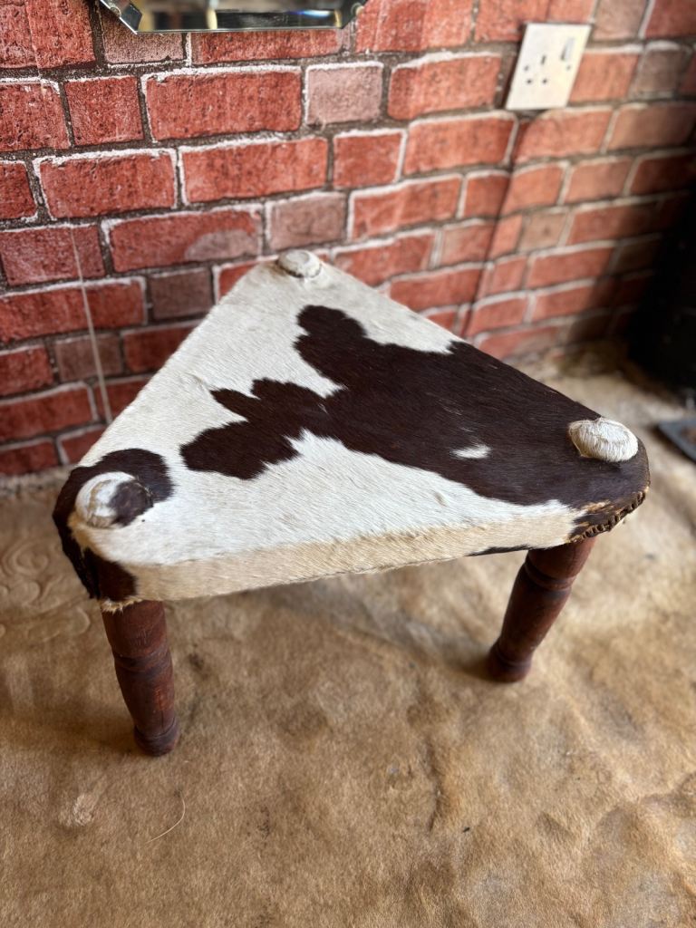 A Vintage Handmade 3 legged stool with cow hide seat.