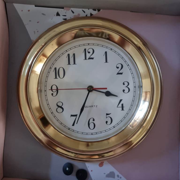 Gold metal frame clock. White face. 3 hands. 