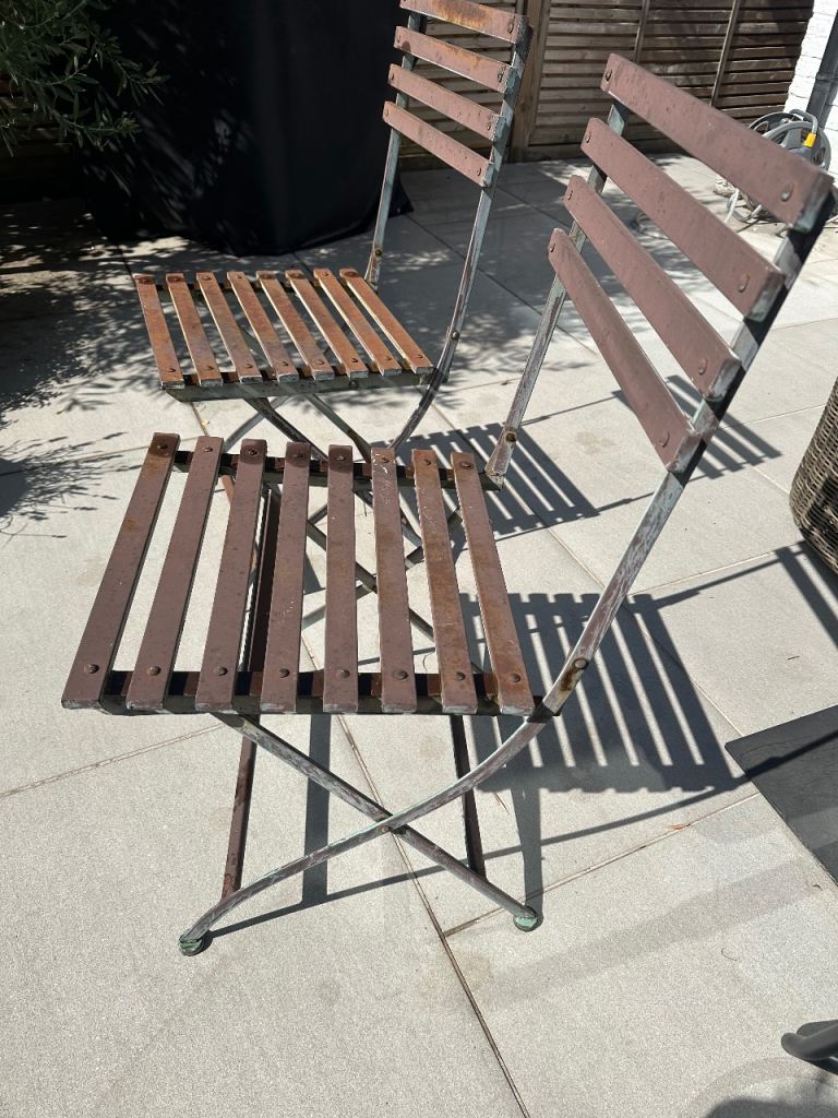A pair of folding rusty metal chairs 