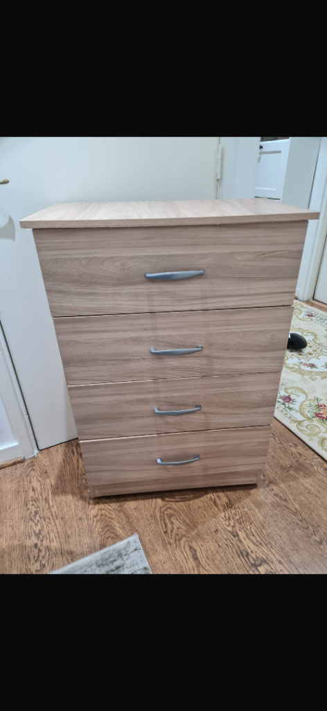 four-drawer chest of drawers with a wood-effect finish and silver-tone handles. 
