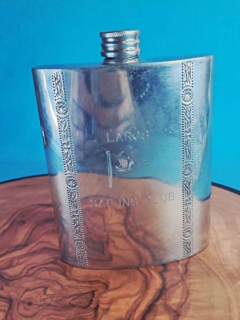This is a vintage pewter hip flask featuring the "Largs Sailing Club" emblem. 