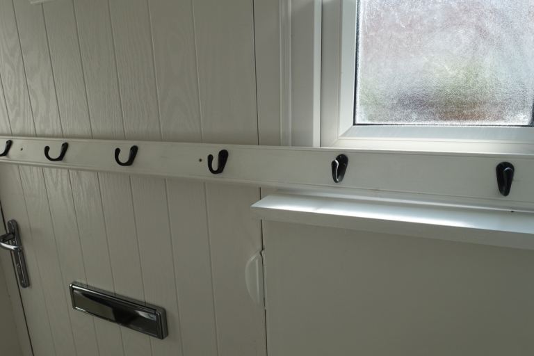 COAT HOOKS MOUNTED ON WHITE WOOD