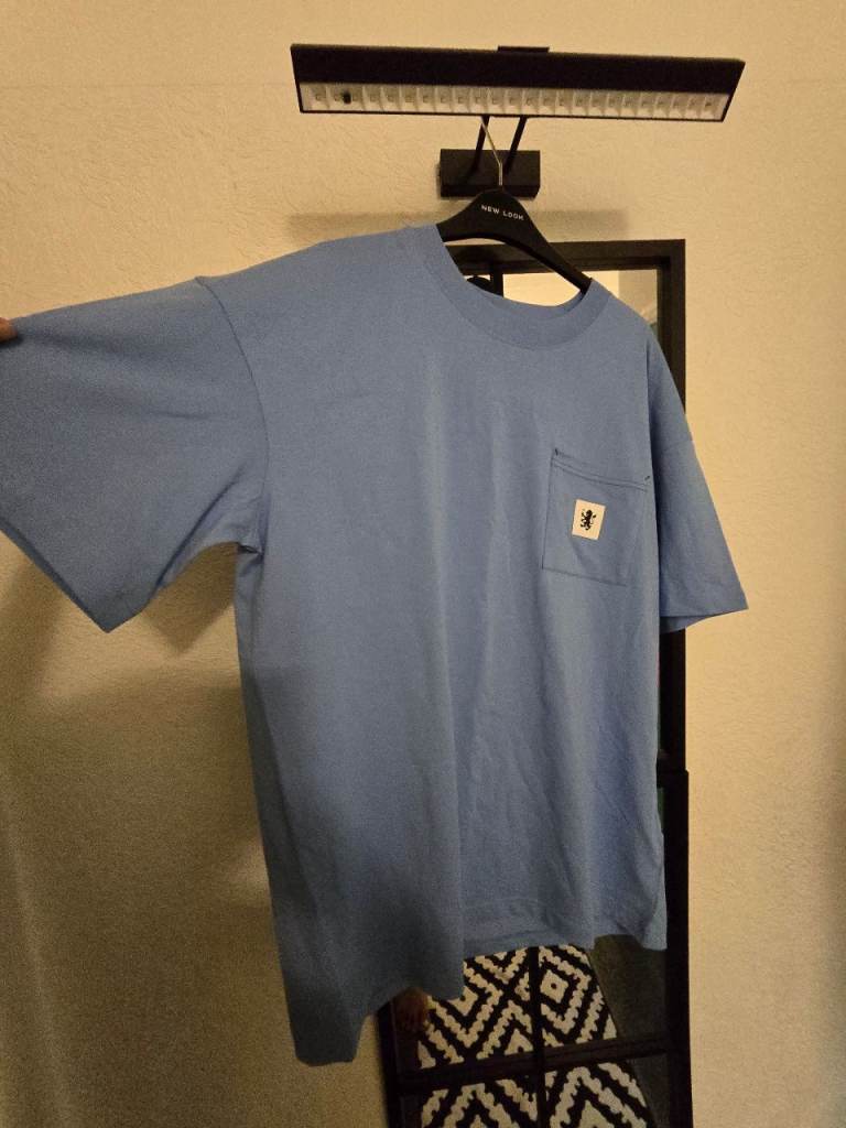 This is a light blue Carhartt WIP short-sleeve pocket t-shirt featuring a square logo label 