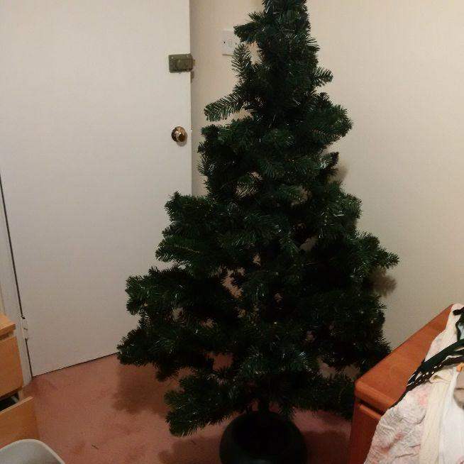 large and substantial artificial christmas tree with a bag of decorations