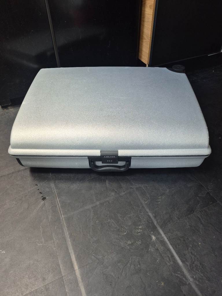 silver Carlton hardshell suitcase features a sturdy black handle and a built-in combination lock 