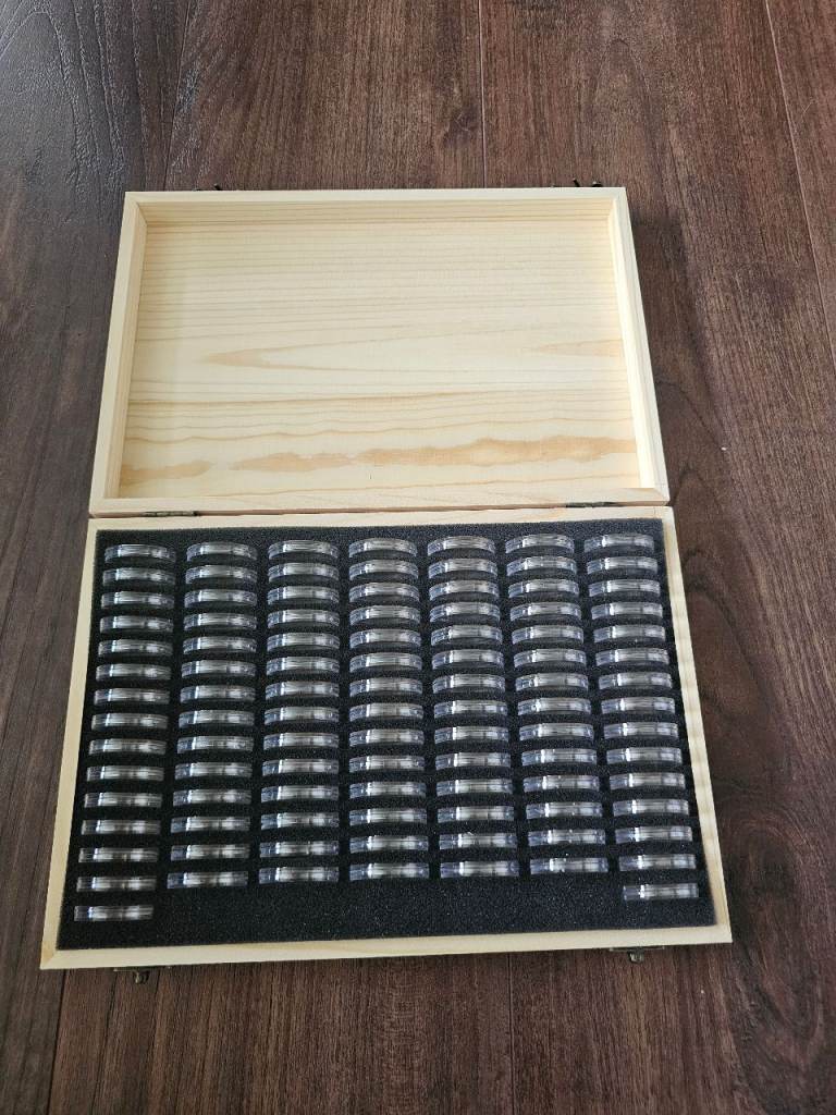 100 coin capsules in wooden box.