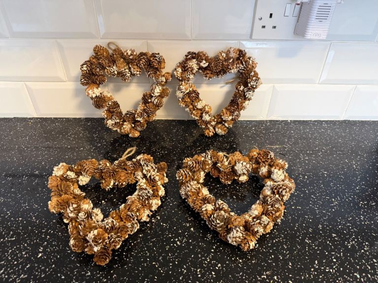 Set of 4 Hanging Heart-Shaped Pine Cone Wreaths with a frosted finish. Approx 8" each.