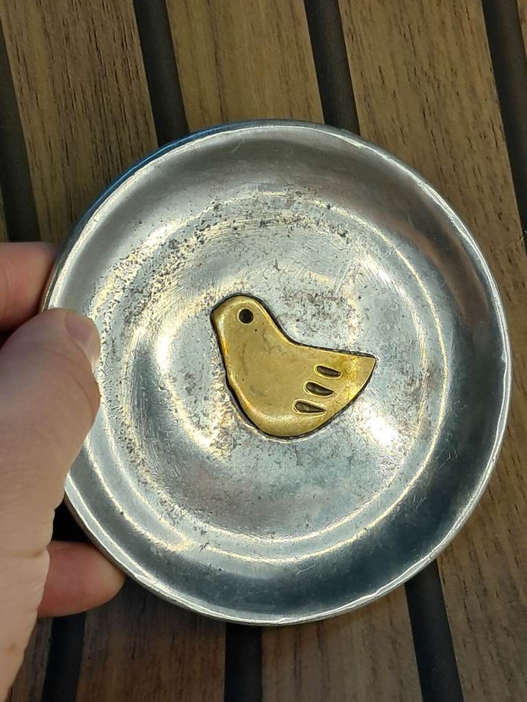 Vintage metal ashtray, made of pewter or a similar metal, with a brass,gold-toned bird inlay. 