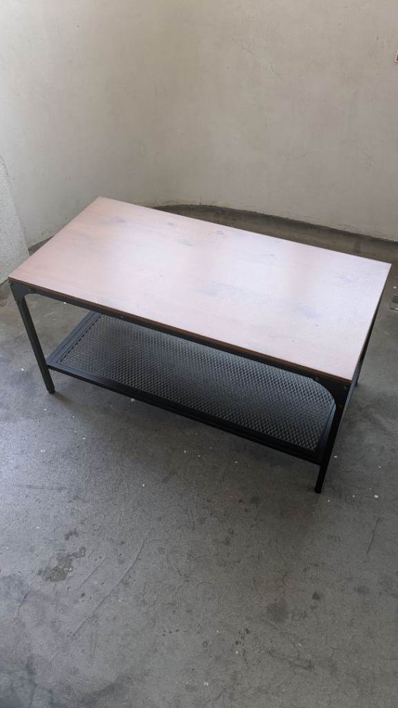 A solid coffee table with a light wood top and black metal frame