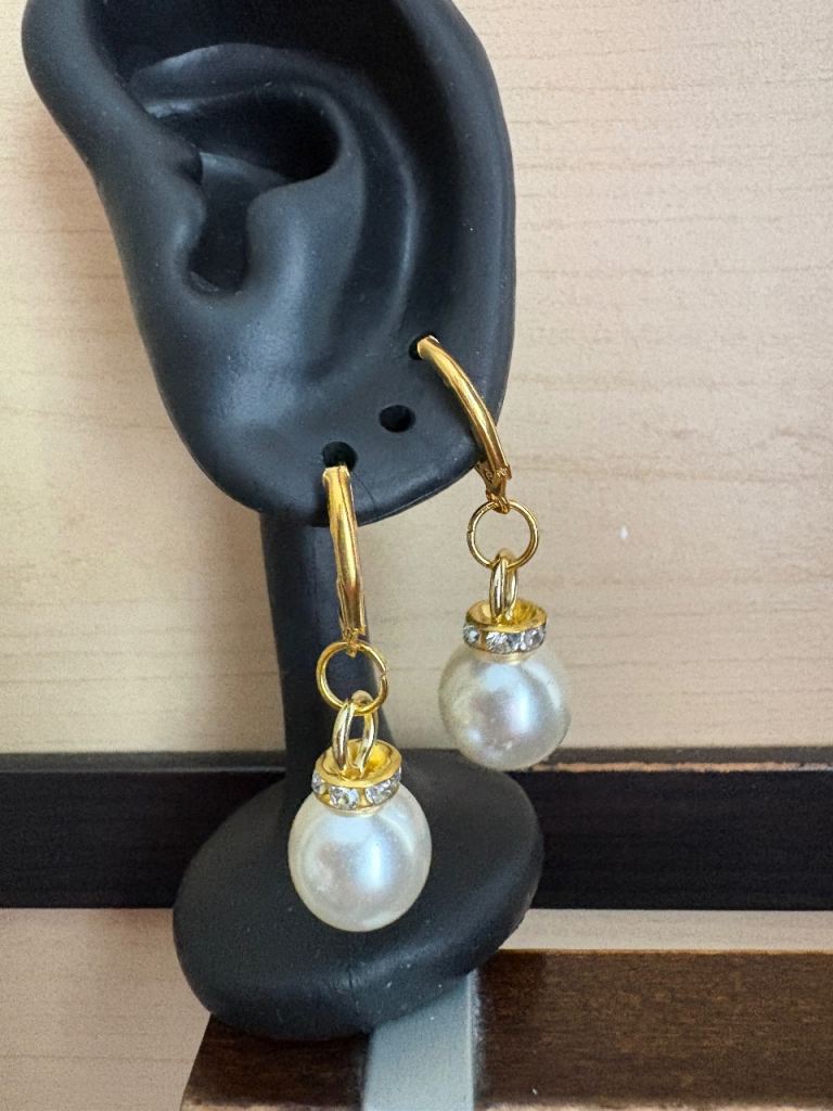 Lovely gold tone hoop earrings featuring elegant faux pearl drops