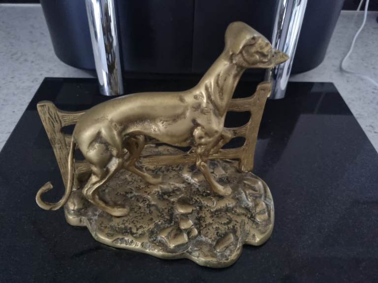 Brass Dog Ornament next to Fence.