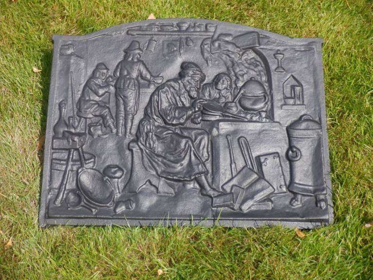 A Vintage style Cast Iron Fireback Plate with a raised  Middle Ages Alchemist Workshop Scene