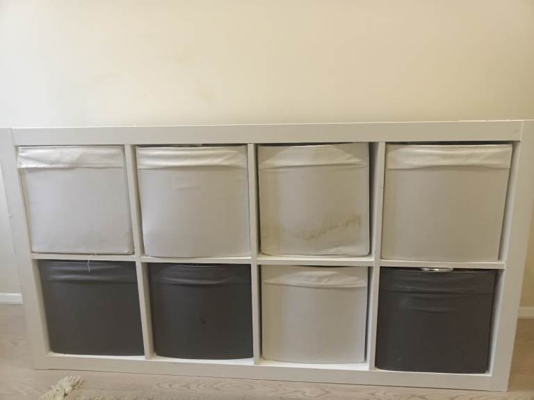 white IKEA KALLAX shelving unit with dark grey and white DRÖNA fabric storage boxes.