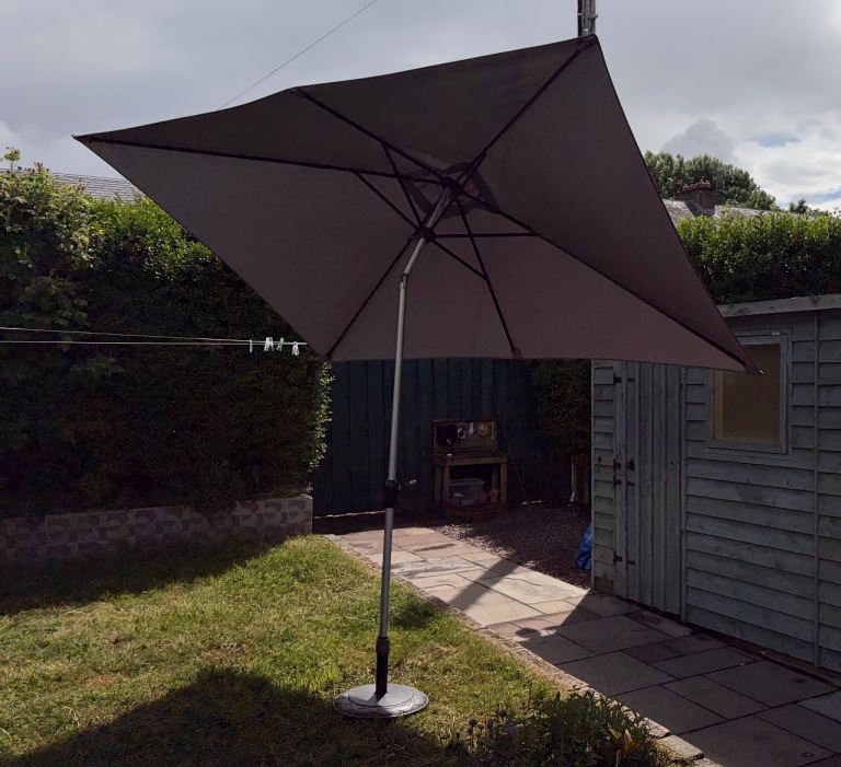 Large tilting parasol with heavy brass base