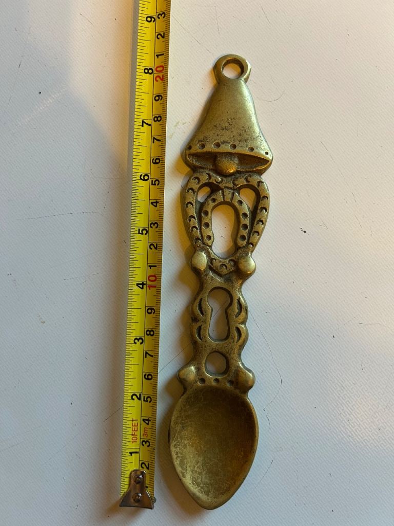 This is a vintage brass Welsh love spoon, a decorative collectible item.