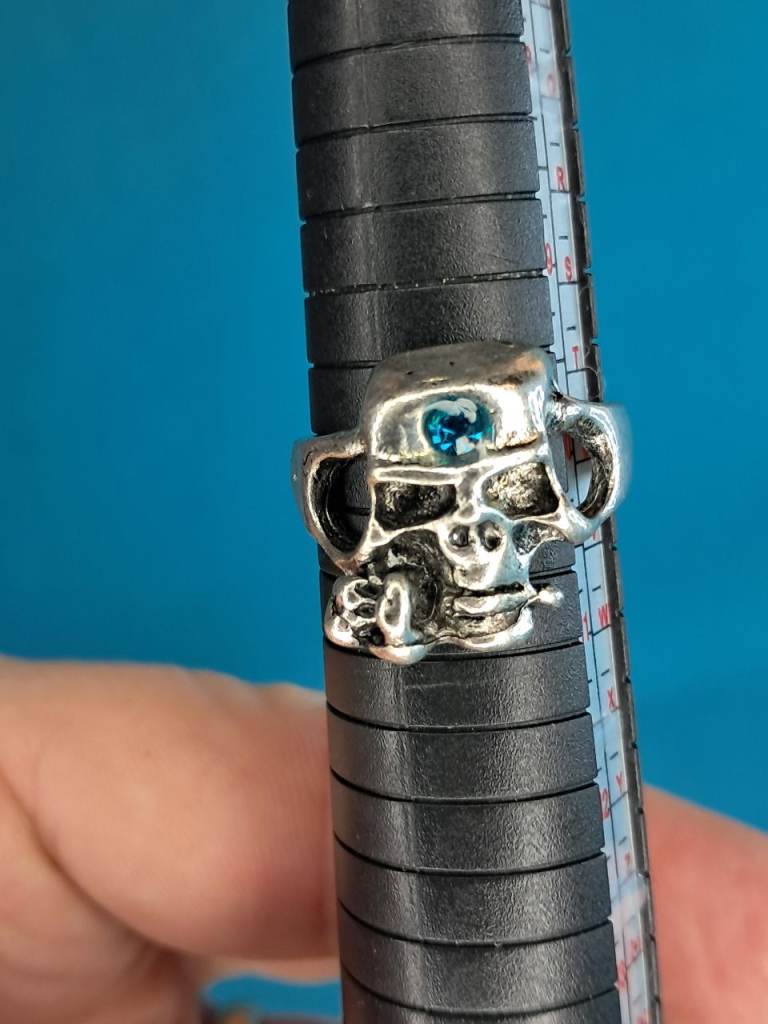 Man's Silver-toned skull ring with a blue gemstone set in the eye socket. 