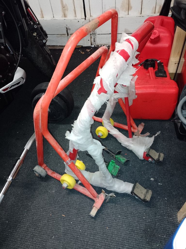 Two Motorcycle paddock stands front and back .