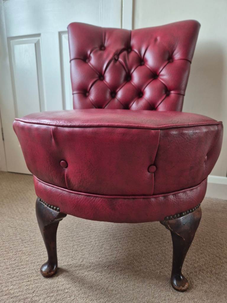 Chesterfield-style chair featuring oxblood leather upholstery and a deep button-tufted back