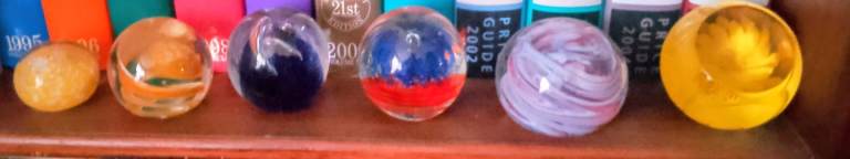 Five large and one small glass paper weights 