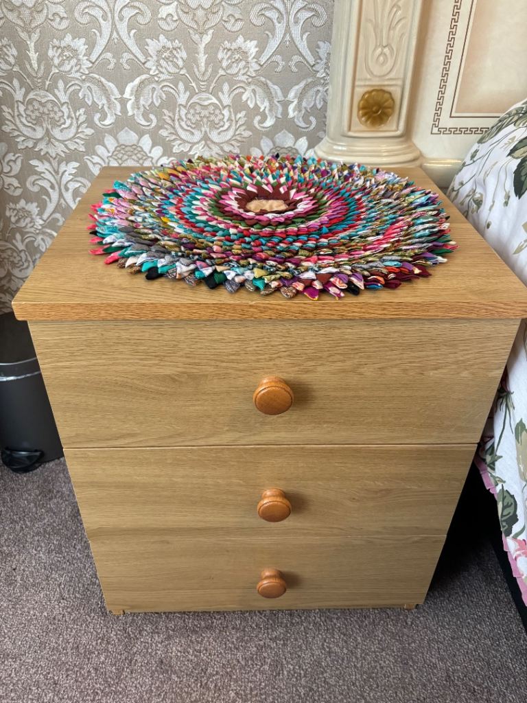 Wooden bedside table with colourful mat