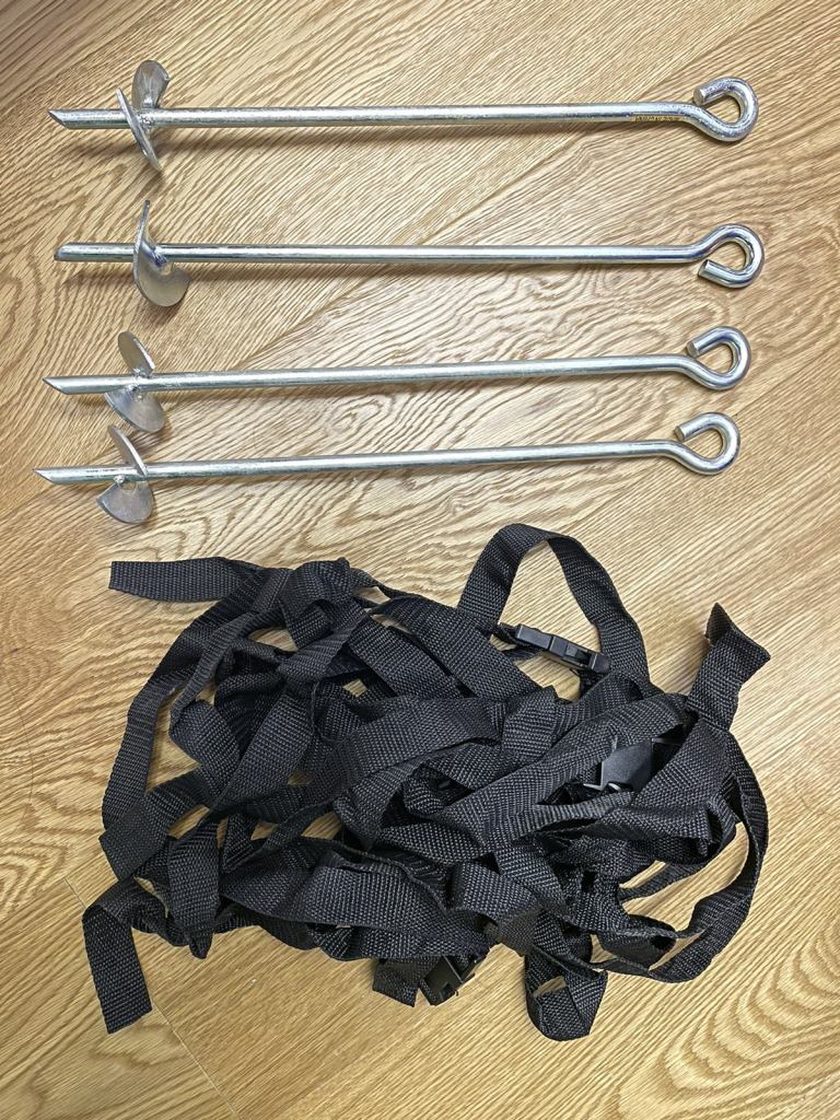 Trampoline tie down screw spikes into lawn with belts