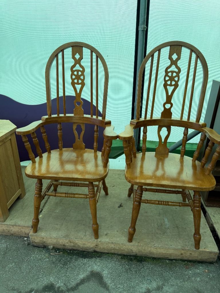 pair of traditional wooden Windsor-style armchairs in a warm honey/oak finish.