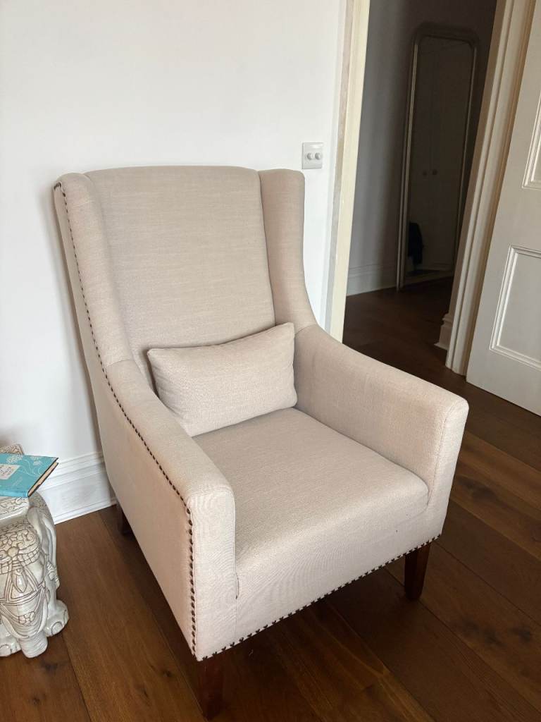 Beautiful armchair in cream fabric with studded details on the armrest