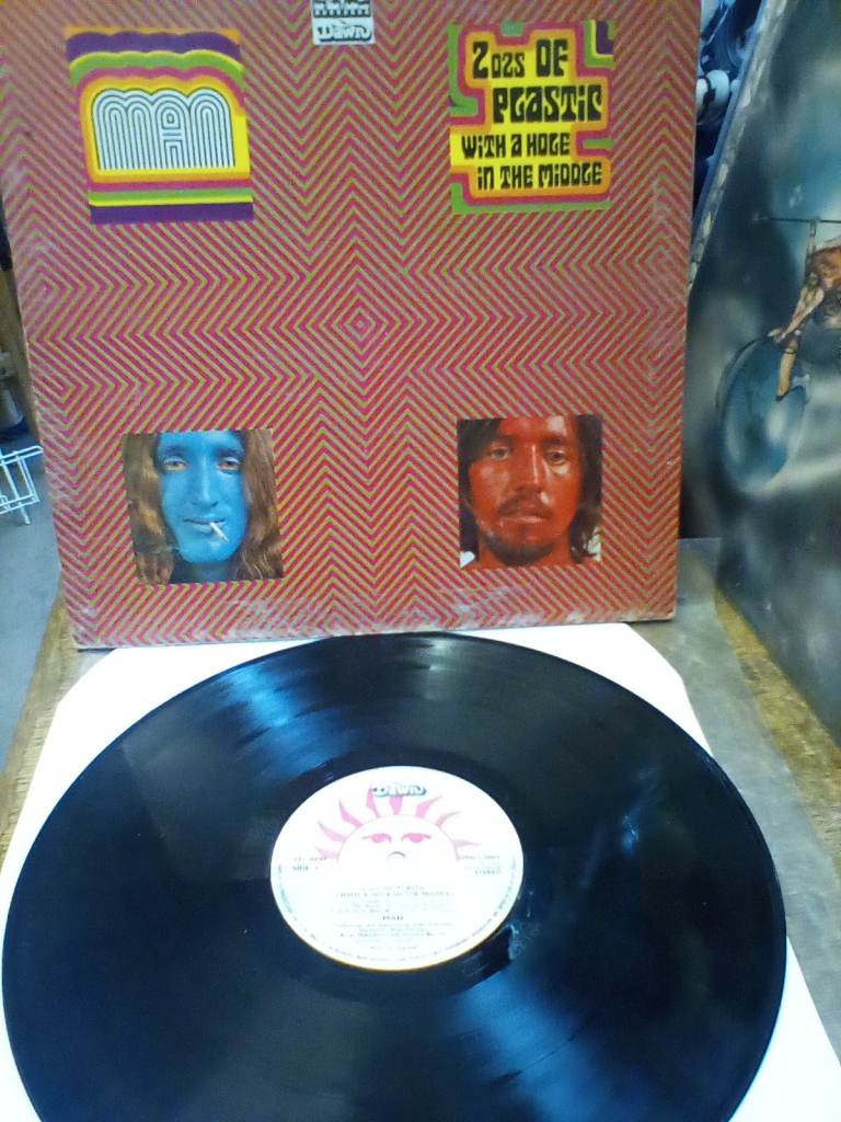 MAN 2 ozs, of plastic with a hole in the middle. Vinyl album