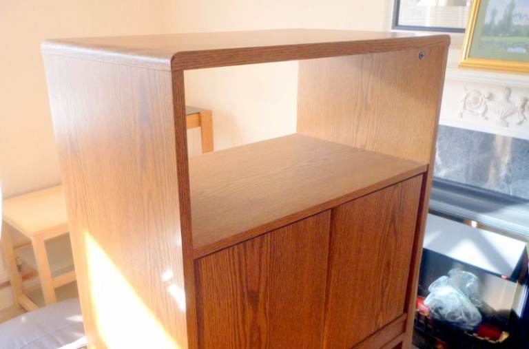 TWO DOOR CABINET WITH SHELF SPACE ABOVE IN LIGHT OAK. IN GOOD CONDITION.