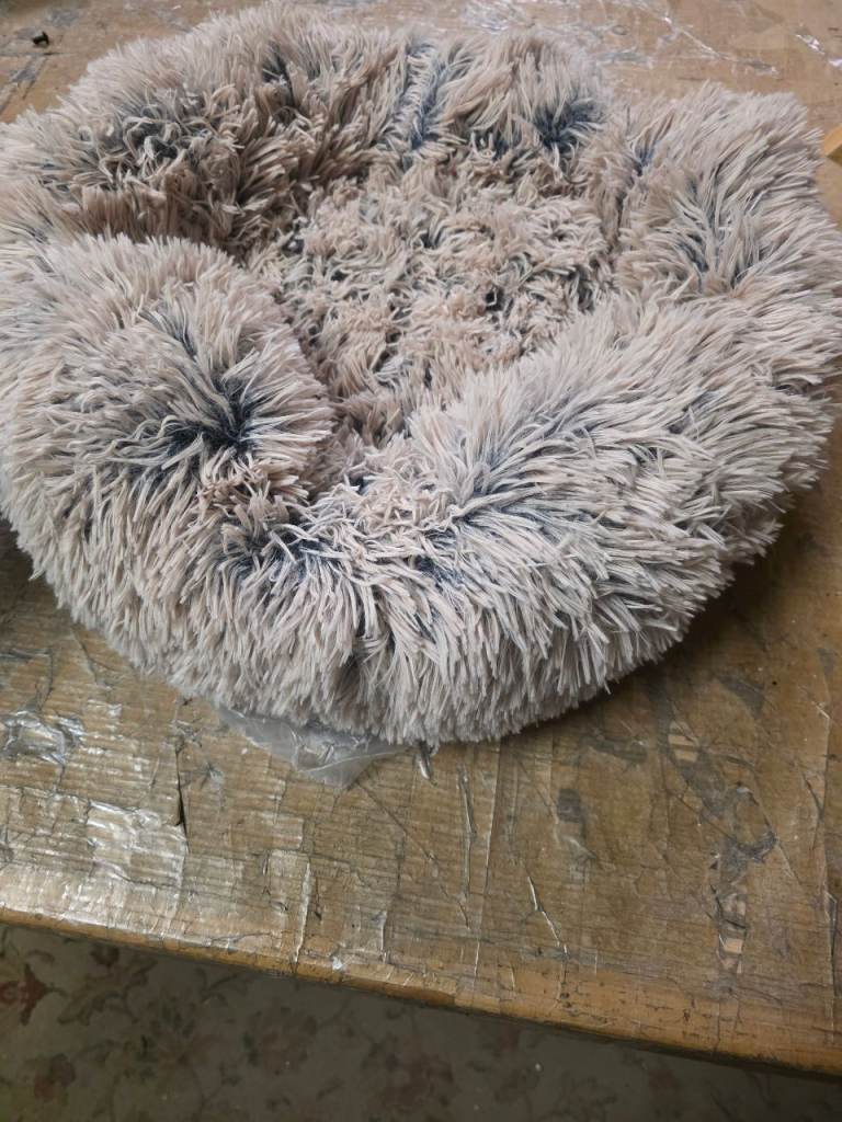 A new small fluffy beige pet bed . 