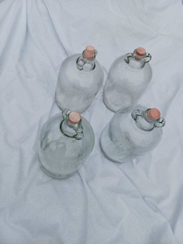 FOUR DEMIJOHNS FOR WINEMAKING WITH STOPPERS.