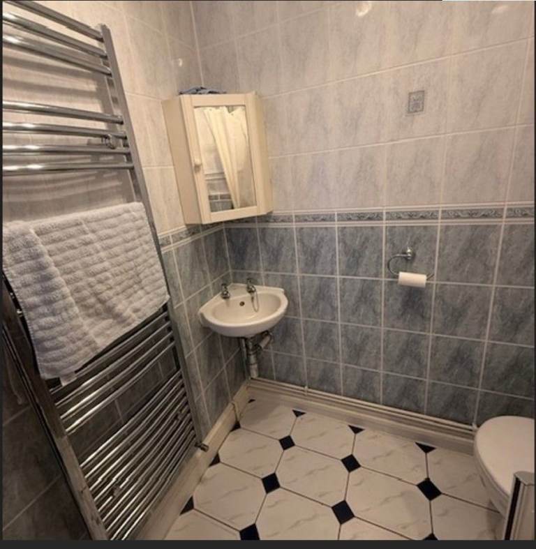 White corner basin with taps, waste fitting and matching corner cabinet with mirror.