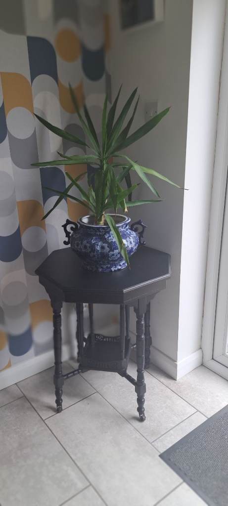 Black ornate hexagonal side table on wheels 