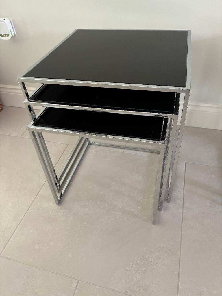 Nest of black glass topped tables set on chrome metal legs