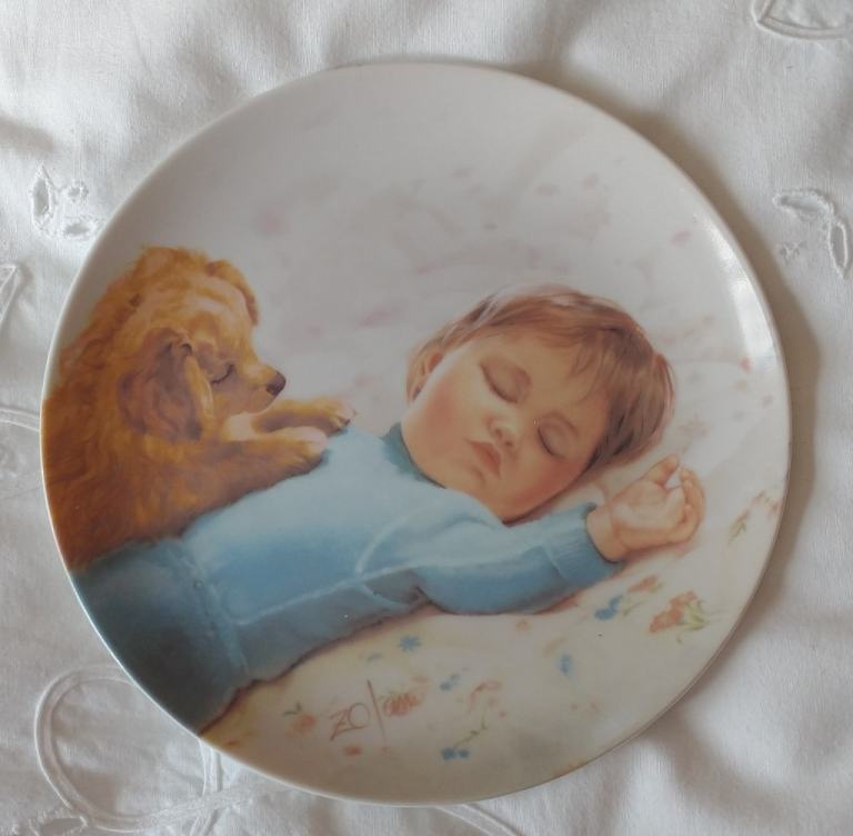 Vintage plate. Young puppy watching a sleeping baby boy