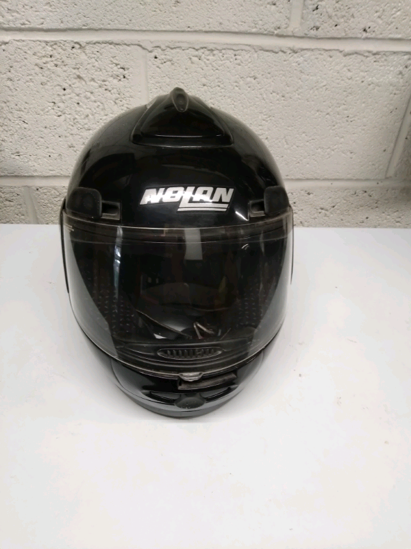 Two black Nolan brand motor cycle helmets.