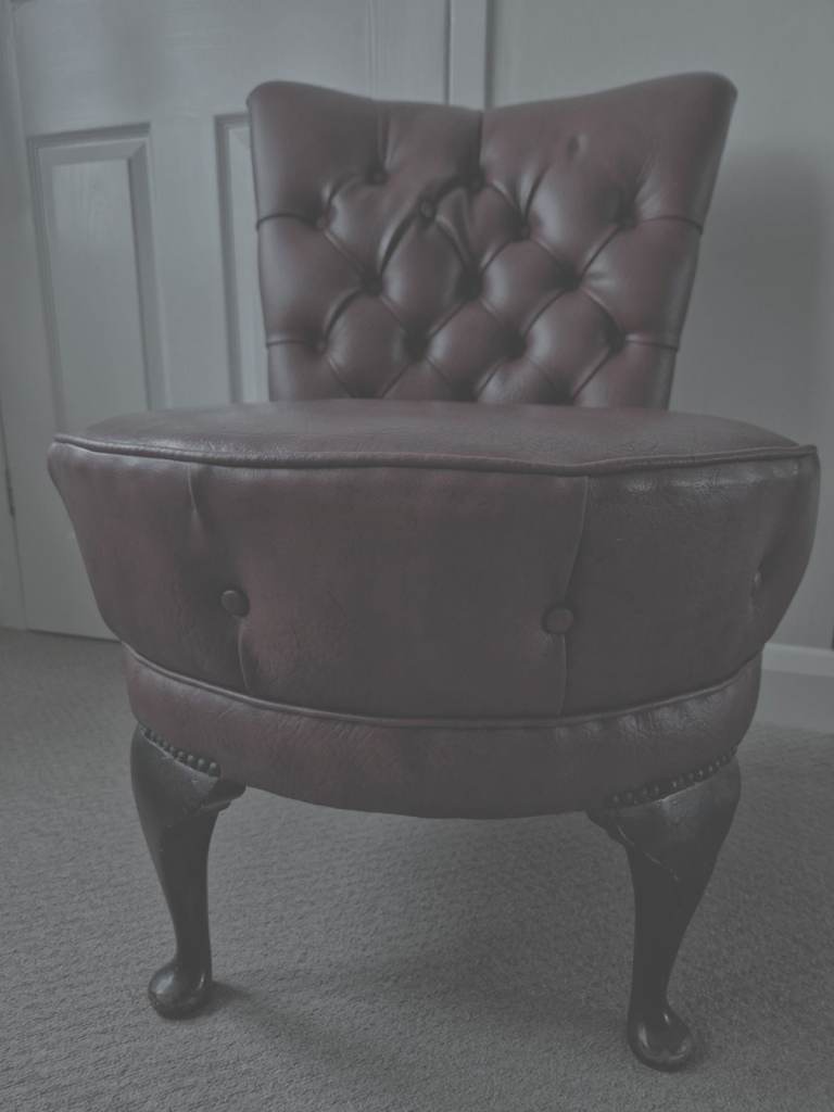 Chesterfield-style chair featuring oxblood leather upholstery and a deep button-tufted back