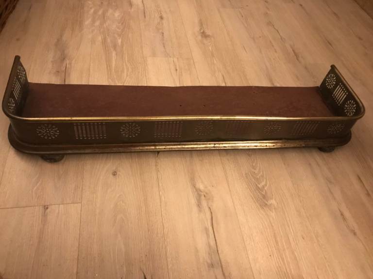 Stylish vintage brass fireplace fender with fretwork.