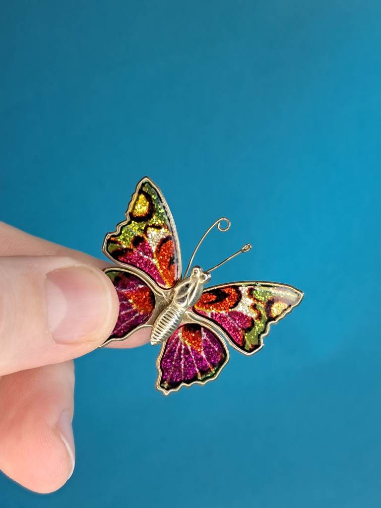 Vintage gold-tone enamel butterfly brooch with multicolored glitter accents. 