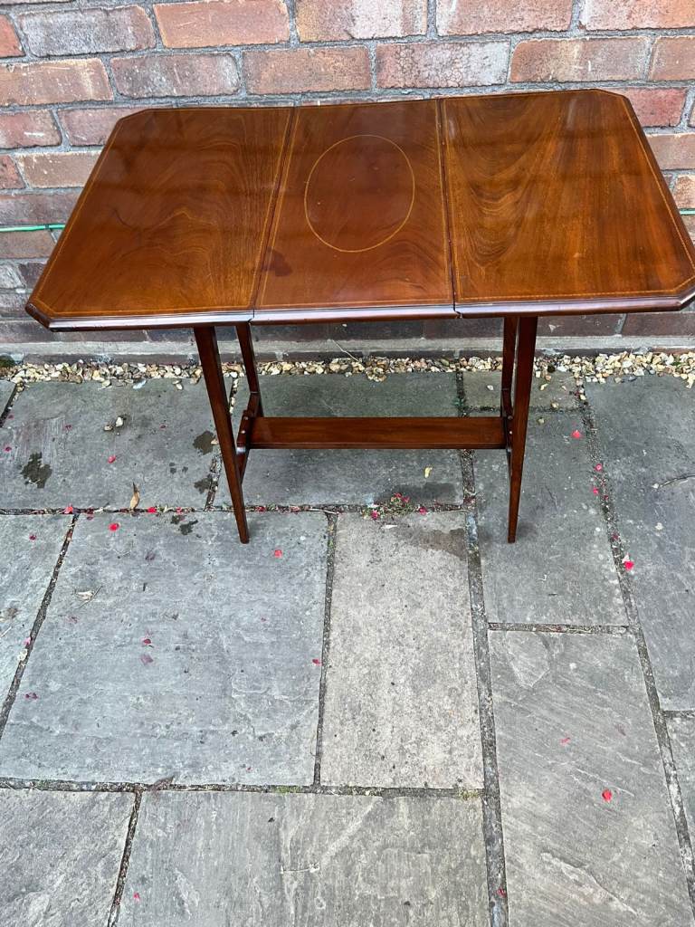 An Edwardian french polished drop leaf table with inlay.