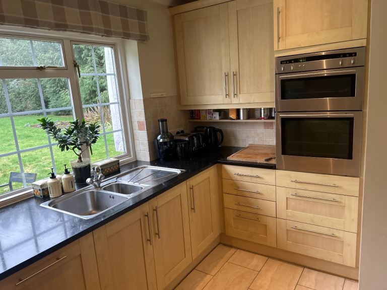 Large kitchen with wood units, integrated hob, oven, sink, dishwasher, rangehood