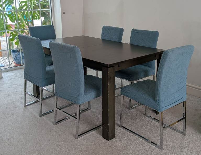 Extendable dining table and chair set, including 6 dining chairs and  6 blue patterned chair covers.