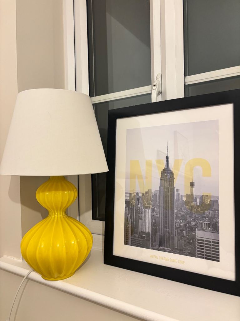 Yellow table lamp with shade and NYC print in frame