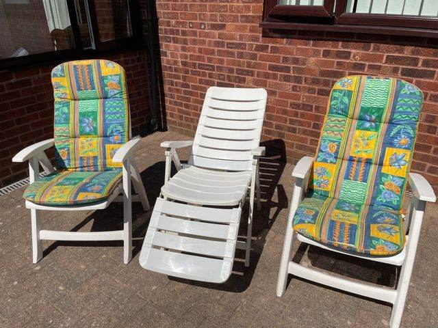 Three White PVC patio chairs, two with cushions plus table