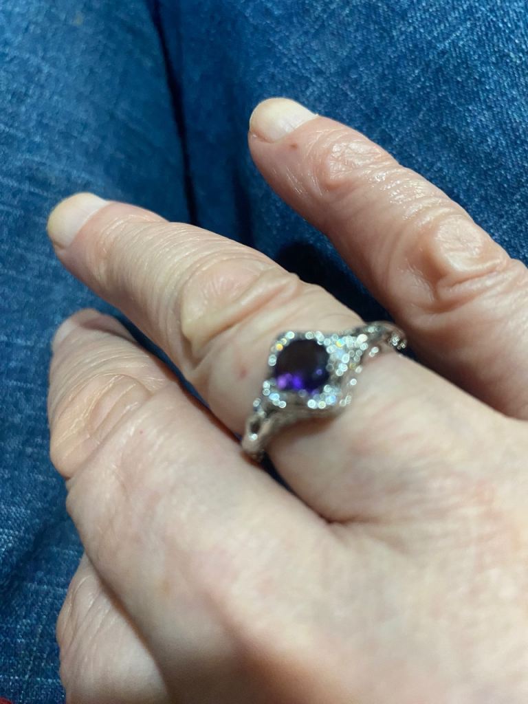 Silver-coloured ring with distinct purple central stone