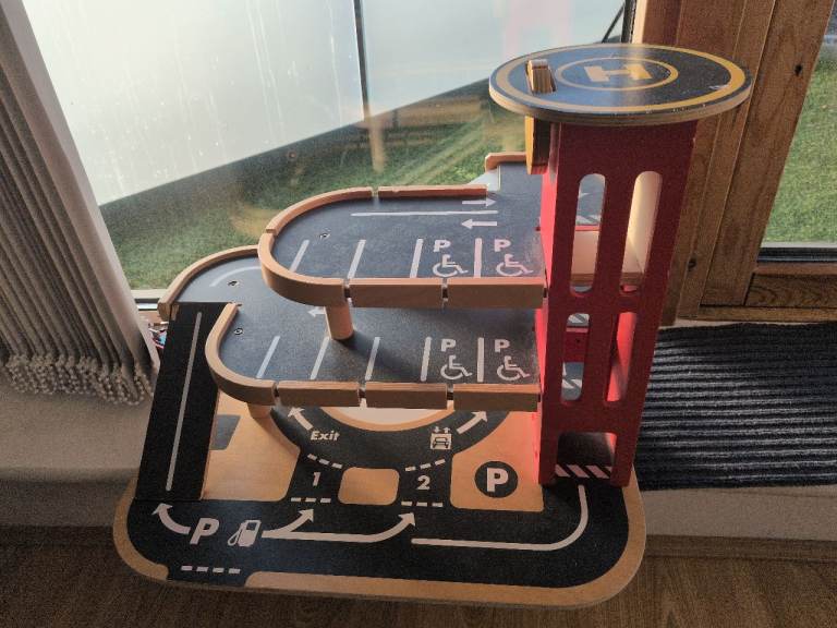 Wooden toy car park with ramps and lift.
