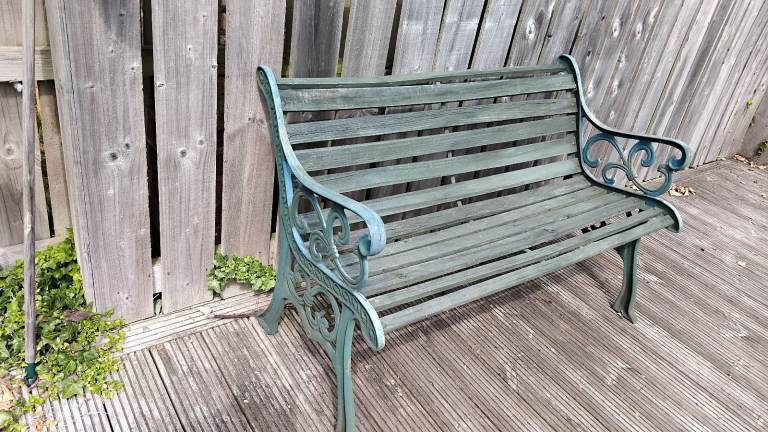 Green wooden garden bench with cast iron arms 