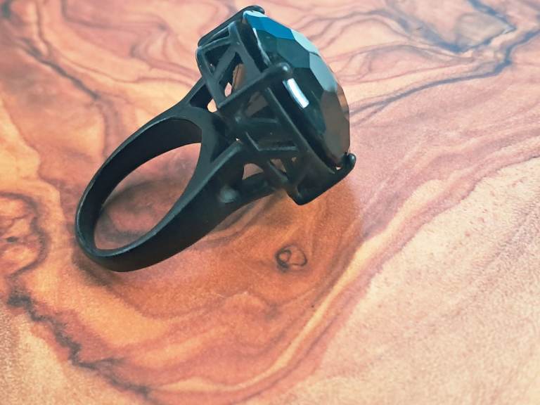 Woman's black gemstone ring, large faceted stone in a dark-colored metal setting.
