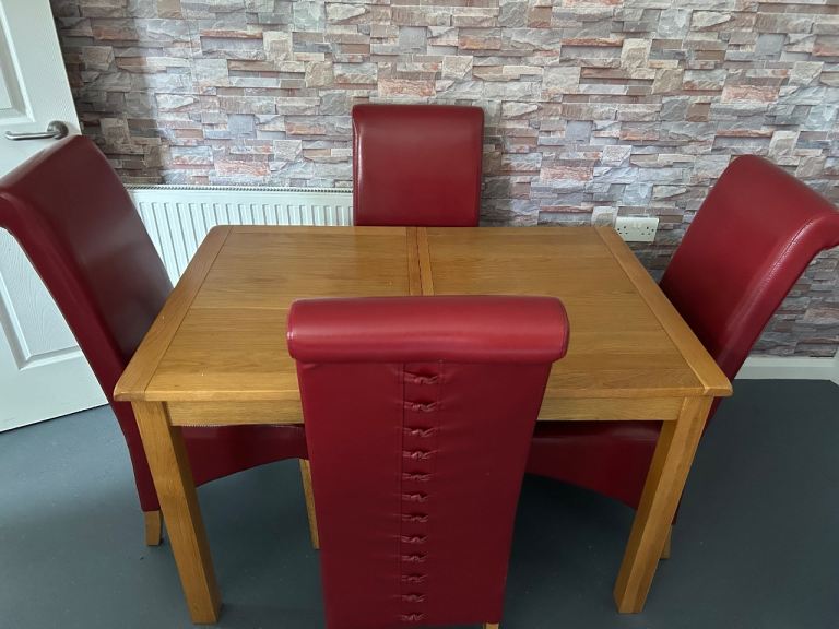 Solid oak 4 seater dining table with four faux red leather chairs 